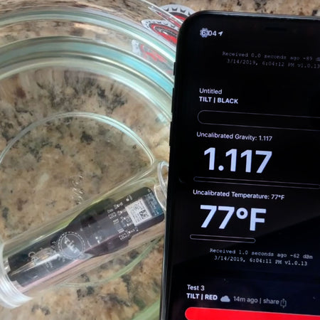 Tilt Hydrometer's App Screen in front of the Tilt in a carboy