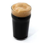 Dark beer with a thick head in a glass on a white background