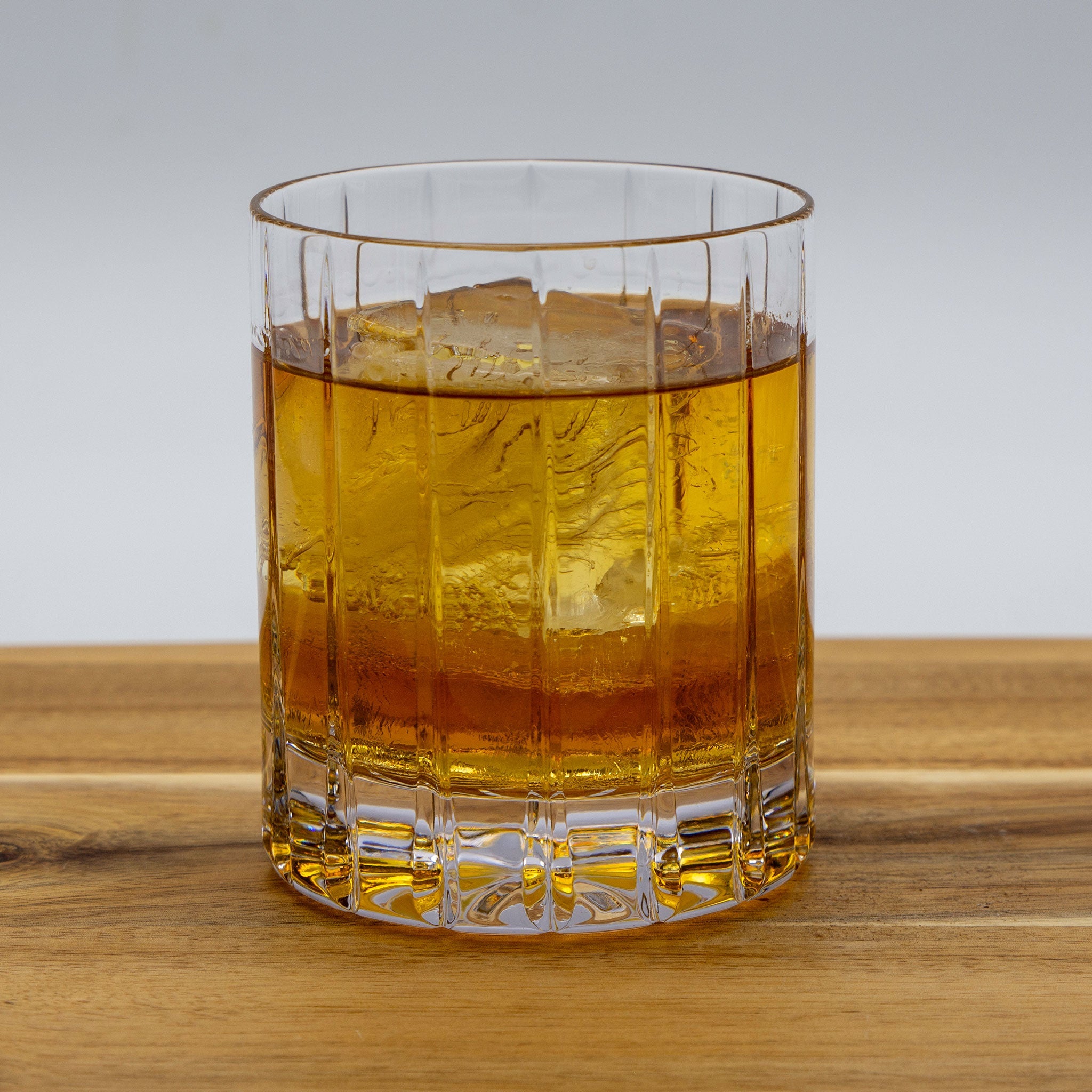 High Rye Bourbon Whiskey in a glass with ice on a wood table.
