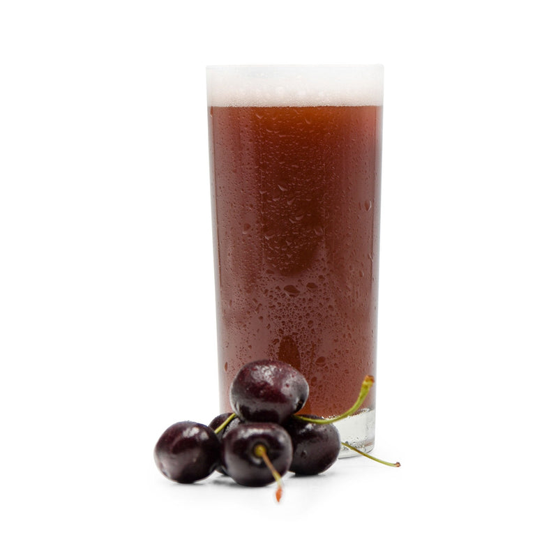 Cherries in a small pile beside a glass of Fruit Stand Wheat Beer