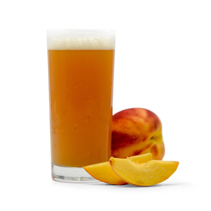 Sliced and whole Peaches next to a glsas of Fruit Stand Wheat Beer