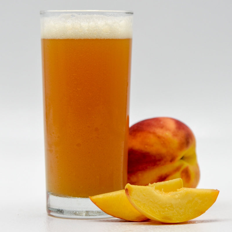 Funktional Fruit Peach Sour homebrew in a glass beside a whole and a sliced peach 