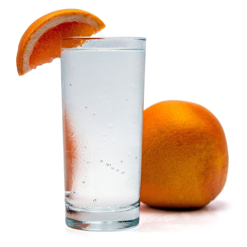 Ruby Red Grapefruit Hard Seltzer in a glass with a grapefruit wedge in front of a whole grapefruit