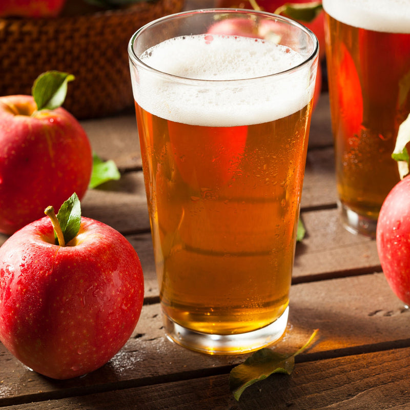 Orchard Fresh Apple Cider in a drinking glass beside apples